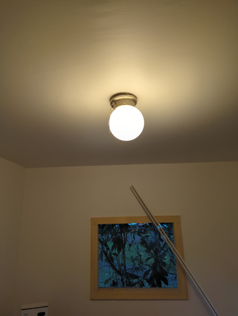 photo of the ceiling light in the studio, illuminated but dangling a bit below the ceiling