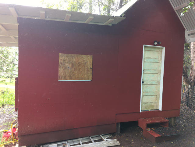 photo of the front of the studio, showing plywood boarding up the window to the left of the front door