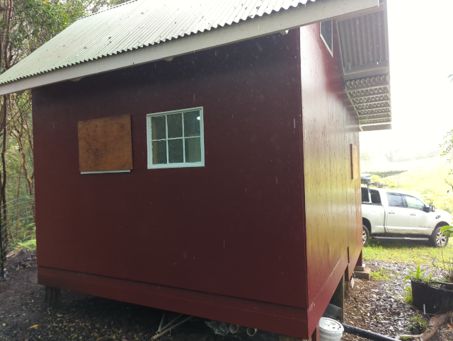 photo of the side of the studio showing a boarded up window, plus another one slightly visible on the back side of the building