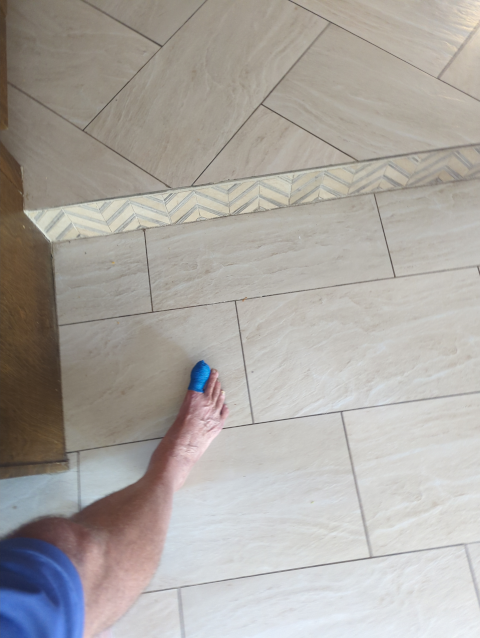 photo of my big toe wrapped in blue horse tape next to a tile step