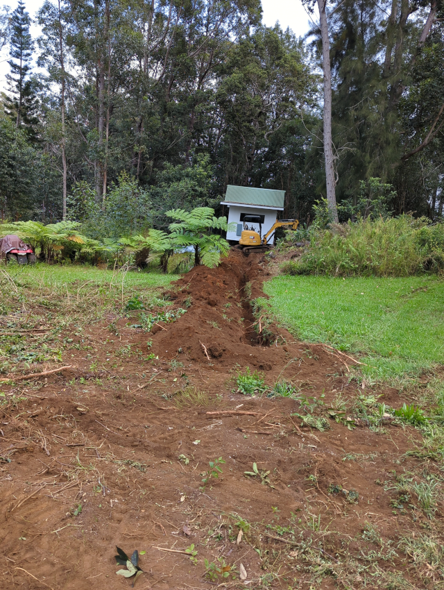 photograph of a freshly dug trench and the excavator responsible