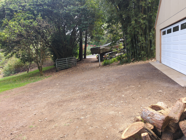 photo of our mostly-dirt driveway with a dumptruck backing in to it