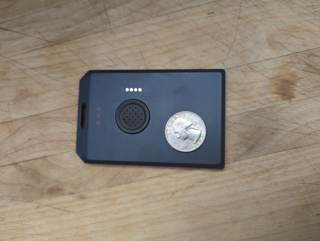 photo showing a WisMesh Meshtastic node; just a flat rectangle of plastic with a US quarter dollar coin for scale